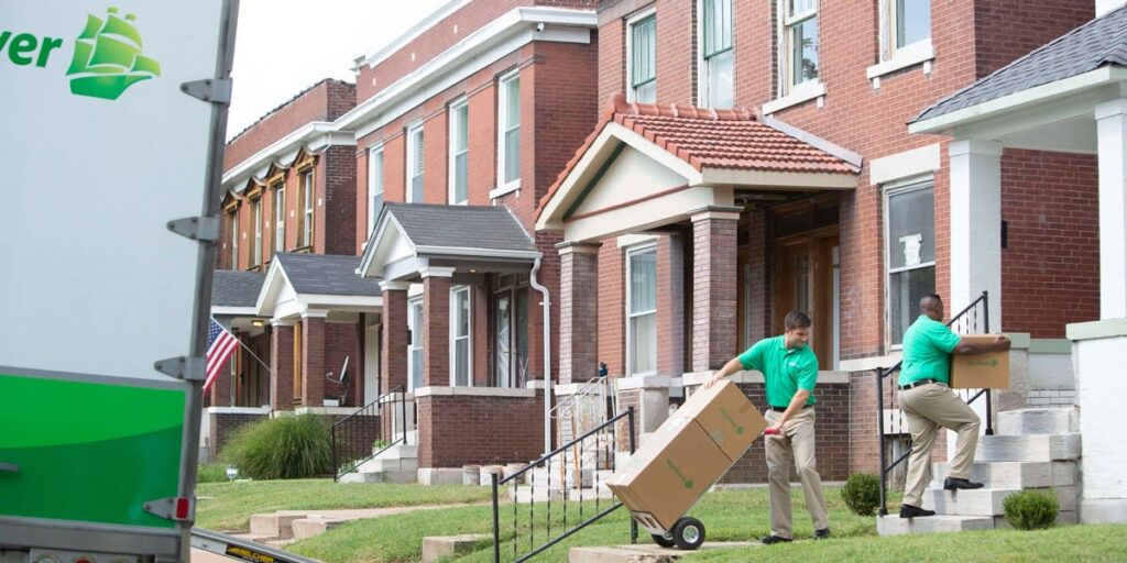 Services 12 movers moving boxes into home with dolly